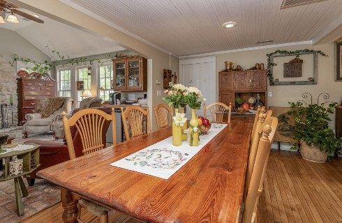 Large oak dining table with seven chairs with a doorway into a living room