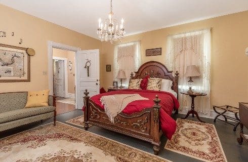 Spacious and elegant guest room with queen bed, two windows, and a upholstered couch