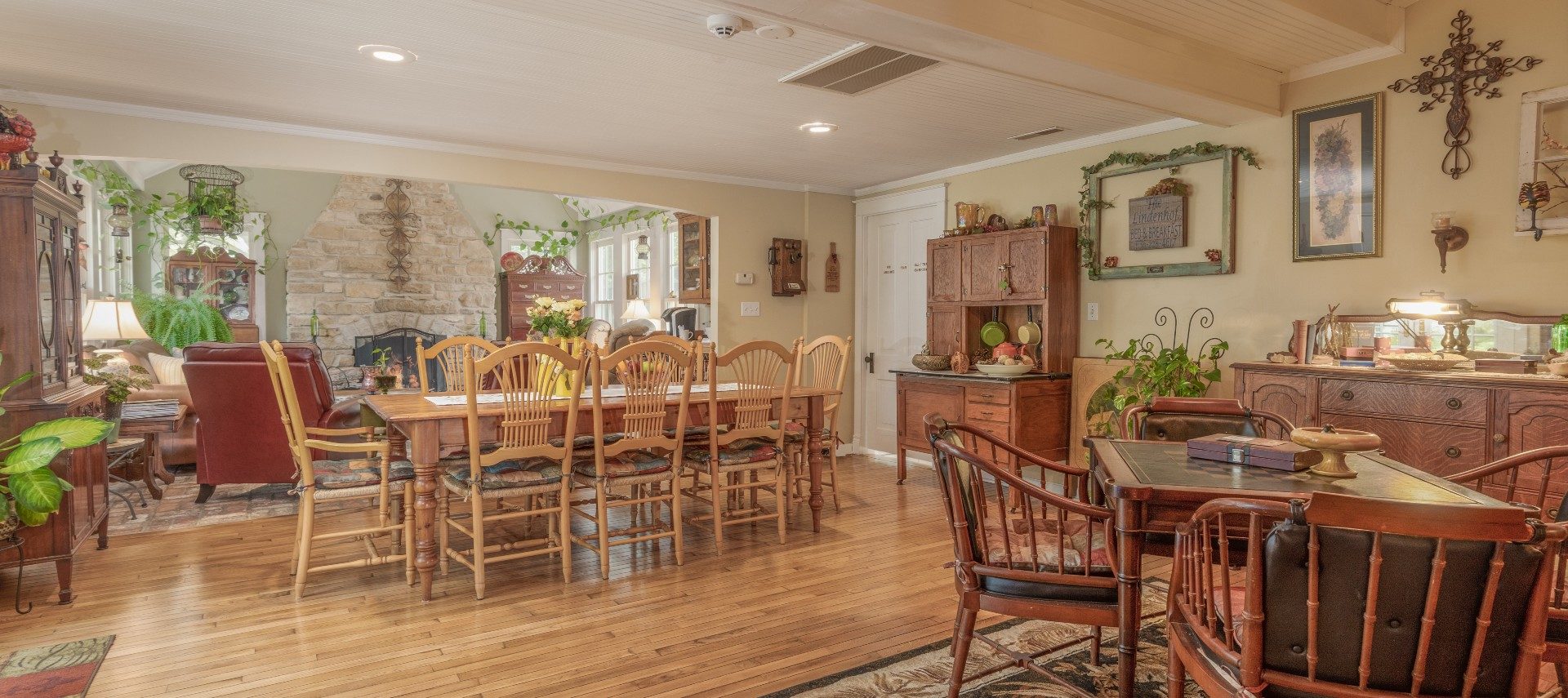 Large dining room of a home with table for eight, table for four and doorway into a fireplace living room