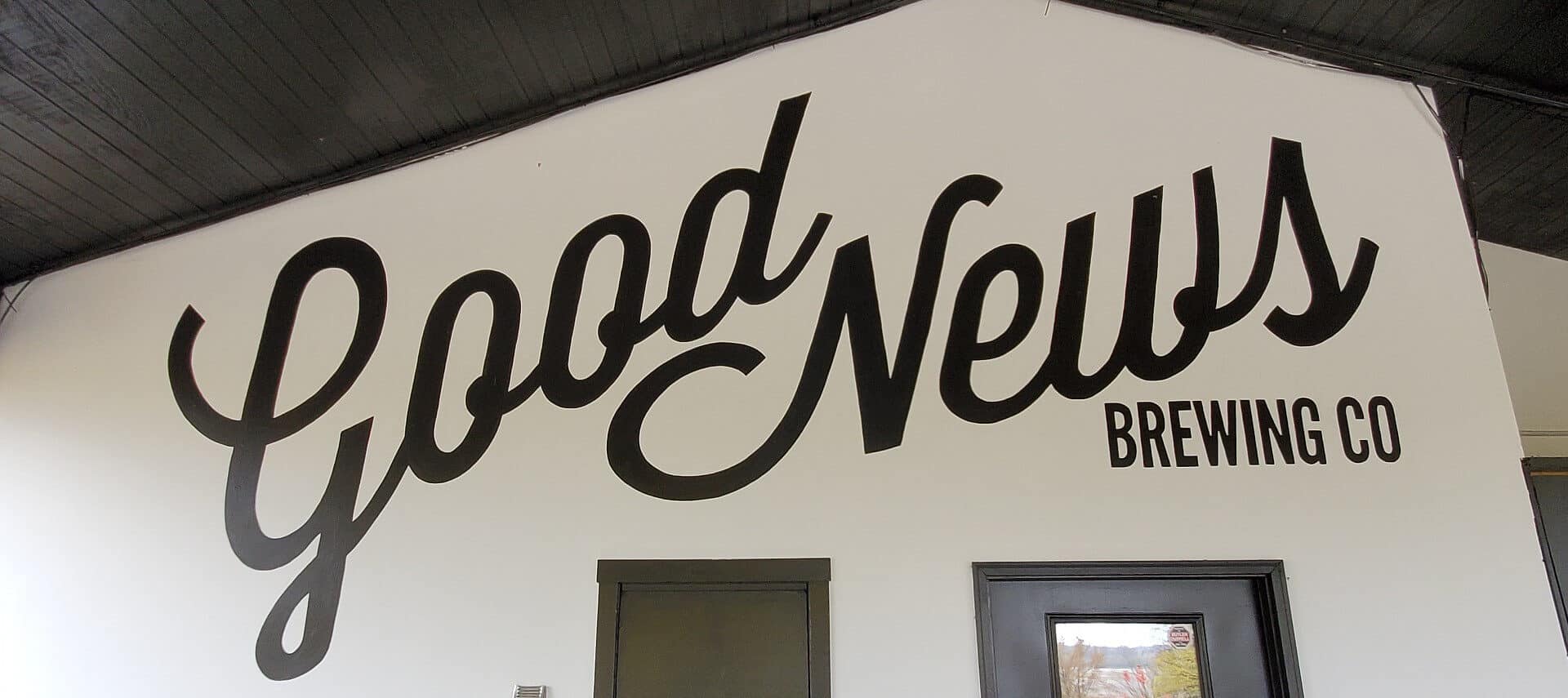 Large white wall with black logo lettering for a brewing company