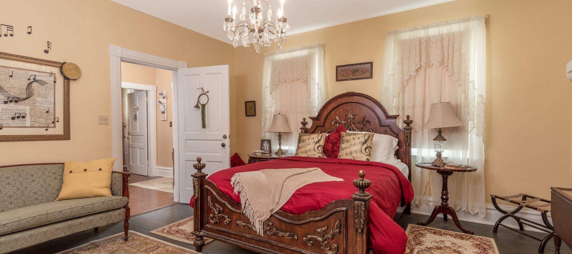 Elegant guest room with queen bed, two windows with drapery and sitting couch