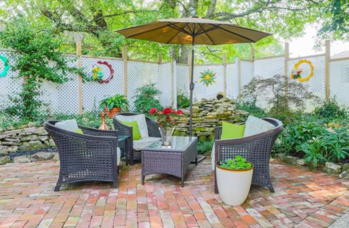 Outdoor patio area with privacy fencing, stone fountain feature and black wicker couch, table and chairs