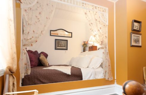 Cozy twin bed in a nook in a room with rust colored walls and white trim