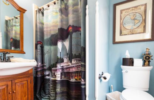 Bathroom with blue walls, stand up shower and single vanity with white sink and large decorative mirror