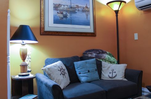 Sitting area in a bedroom with a blue loveseat, framed art and two lamps