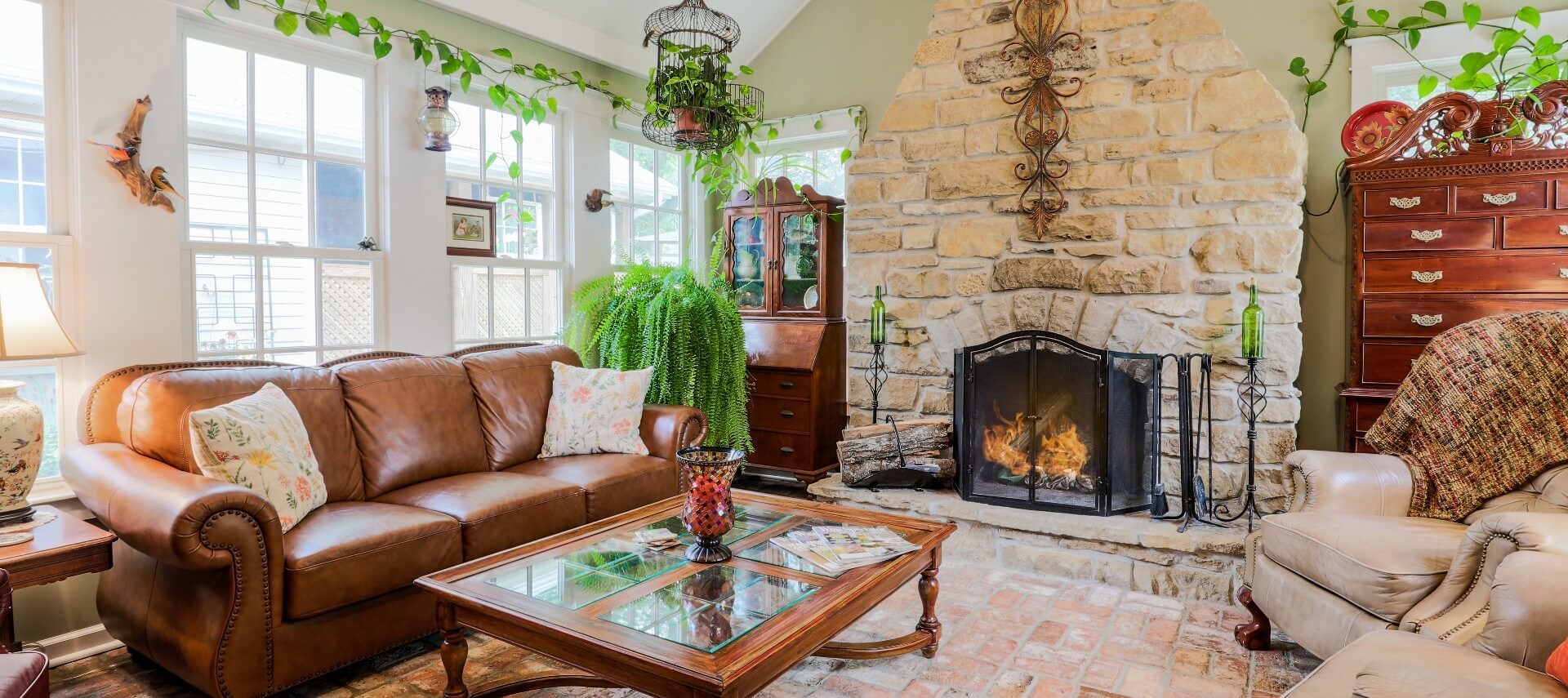Cozy living room with large stone fireplace, large windows and leather furniture