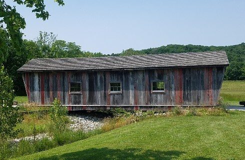 An old covered bridge with multicolored wood boards and three windows
